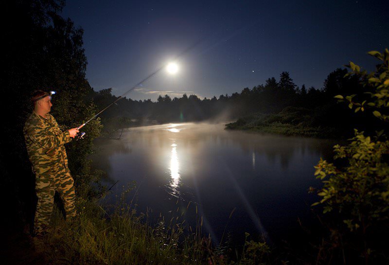 Мужчина рыбачит ночью